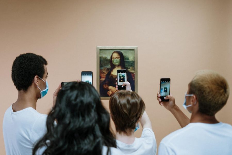 Students wearing masks photograph a version of The Mona Lisa, who is also wearing a mask.